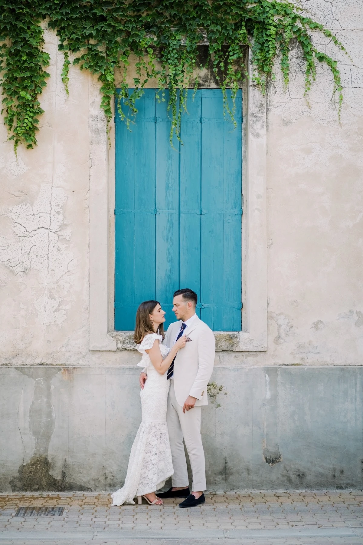 Due sposi di un matrimonio in provenza Francia in un vicolo davanti ad una finestra blu