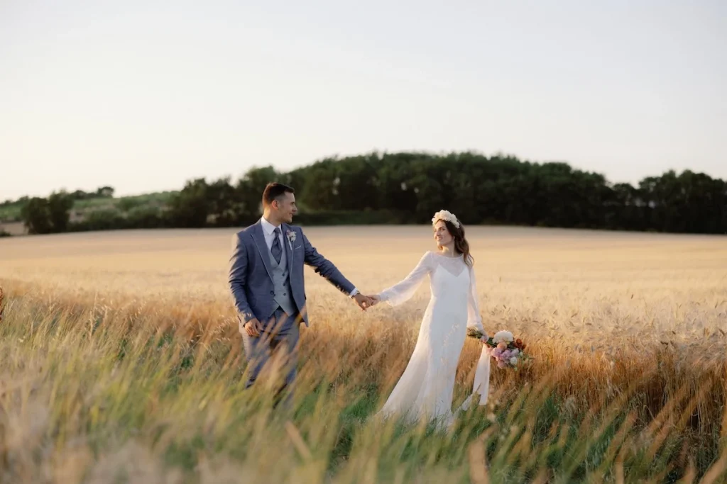 due sposi mano nella mano in un campo di grano